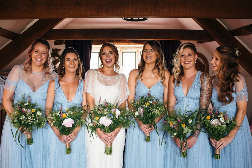 Bride with five bridesmaids in blue holding bouquets at Ash Barton