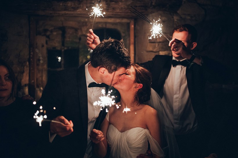 Bride and groom kiss while holding sparklers at winter wedding venue Ash Barton