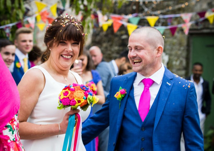Colourful bride and groom celebrate with buying at Ash Barton Devon wedding venue