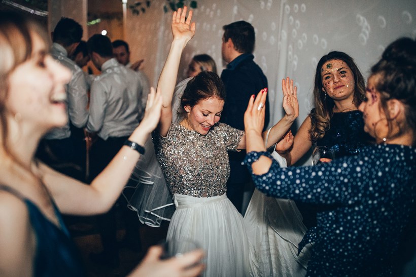 A bride wearing a glitter top dances at Ash Barton Wedding Venue