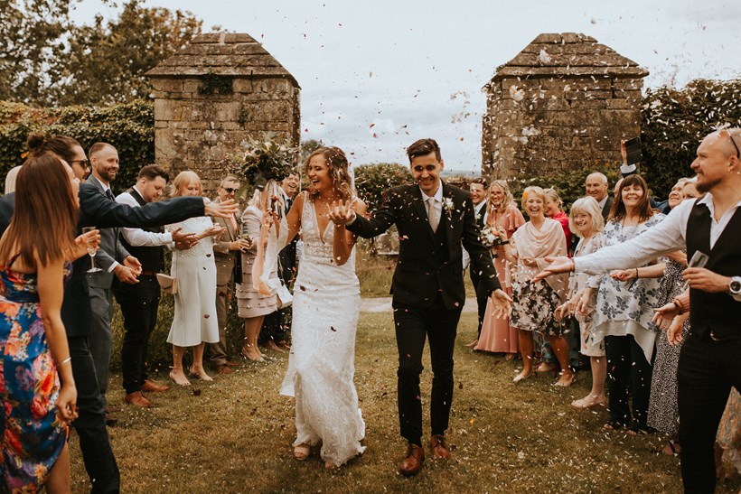 Bride and groom walk through confetti at Ash Barton