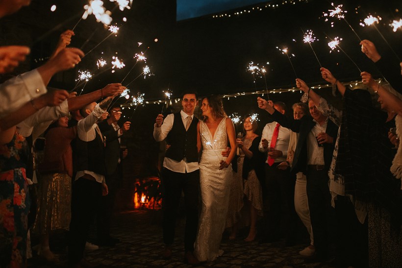 Bride and groom walk through arch of sparklers