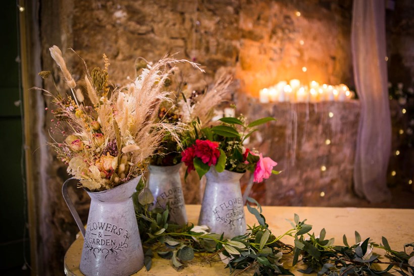 Jug of dried grass and flowers with candles