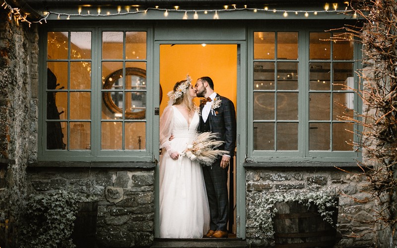 Ashbarton Estate - Bride and groom kiss in doorway at Ash Barton wedding venue Devon