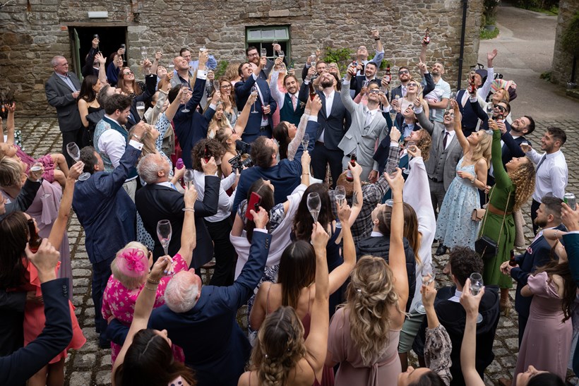 Wedding guests making a toast in courtyard at Ash Barton Devon wedding venue